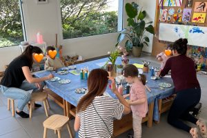 Drei Mütter malen gemeinsam mit ihren Kindern am Tisch im Atelier von Tiny Hands Creations in Zürich