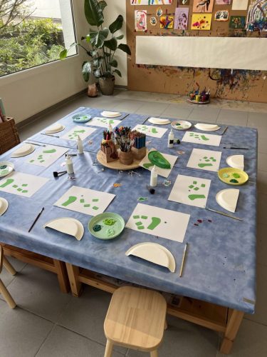 Kinder basteln einen Dinosaurier aus zugeschnittenen Körperteilen, die am Basteltisch aufgeklebt werden, bei einer Dino-Geburtstagsparty in Zürich