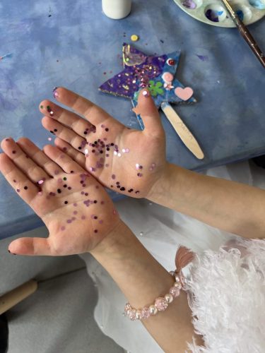 Nahaufnahme von Kinderhänden mit Glitzer und Feenstab am Basteltisch bei einer Märchenland-Geburtstagsparty von Tiny Hands Creations