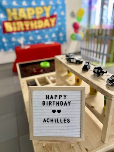 Innenansicht einer Paw-Patrol-Geburtstagsparty mit Fotoleinwand „Happy Birthday“, Sensorik-Tisch mit Spielzeugautos und Helikoptern bei Tiny Hands Creations
