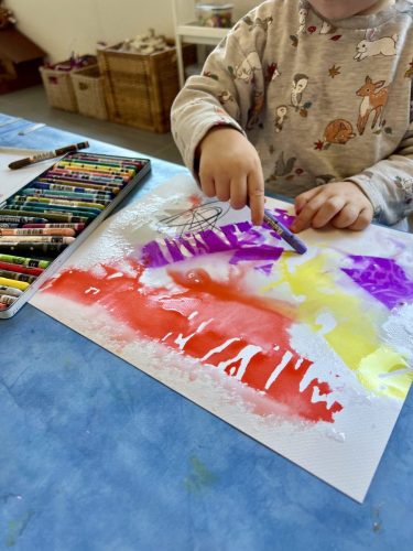Kind gestaltet mit Krepppapier, Wasser und Crayons ein buntes Kunstwerk im Atelier von Tiny Hands Creations