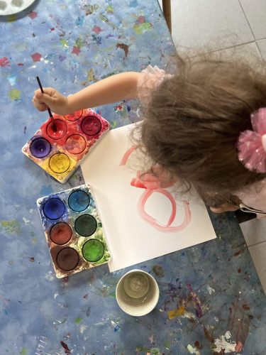 Kind malt konzentriert mit Wasserfarben, Blick von oben auf das Kunstwerk im Atelier von Tiny Hands Creations