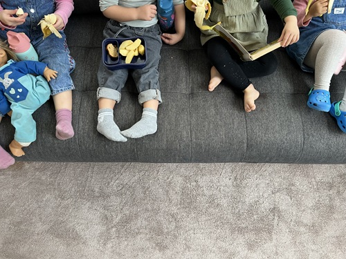 Vier Kinder sitzen gemeinsam auf dem Sofa und genießen ihr Znüni in der Spielgruppe in Zürich.