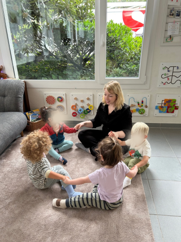 Kinder sitzen gemeinsam in der Spielecke beim Morgenkreis in der Spielgruppe von Tiny Hands Creations